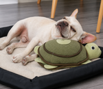 Dog lying on a bed with a turtle-shaped toy